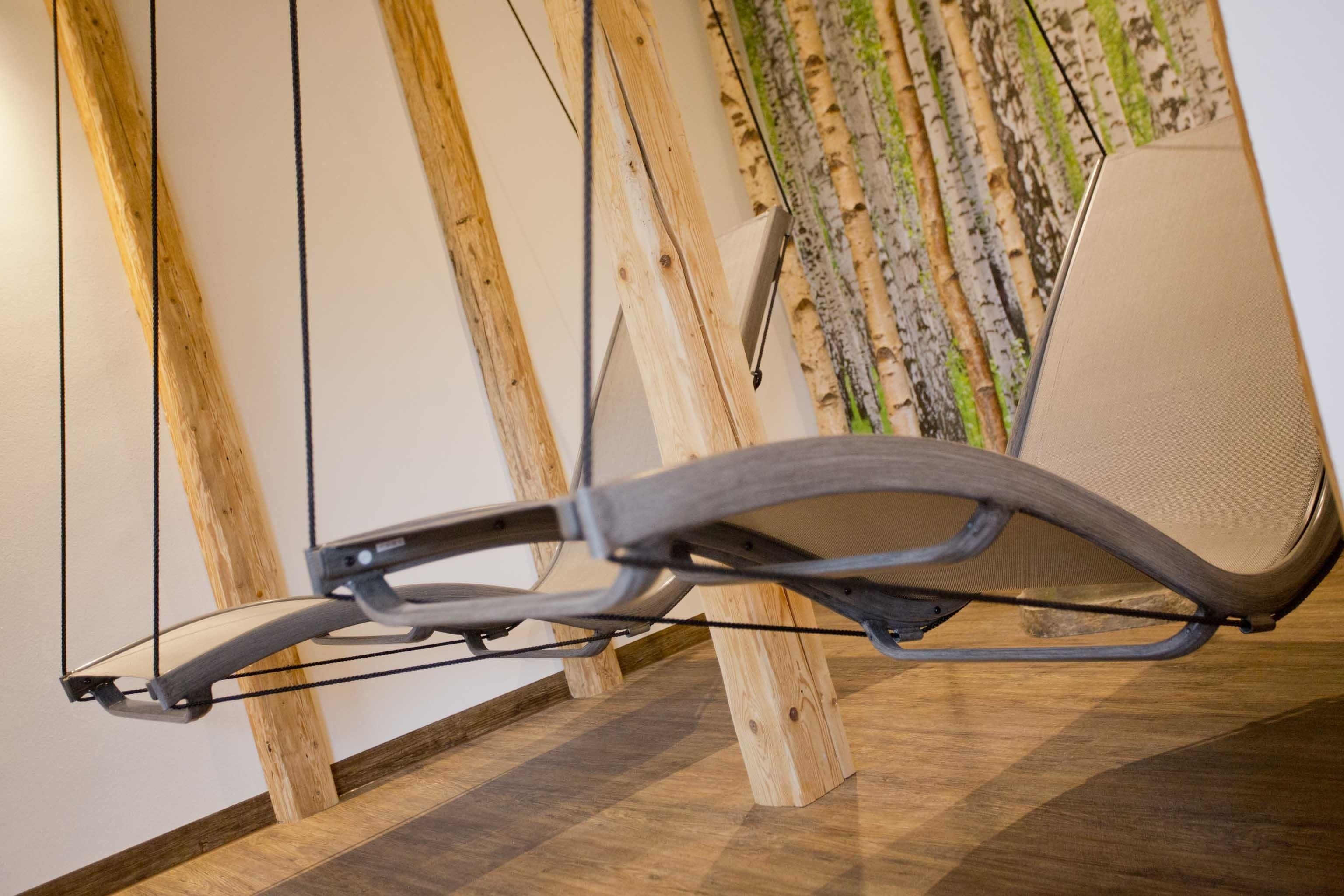 A modern chair with a metal frame and a cushion, positioned against a wall with wooden beams and a textured wallpaper.