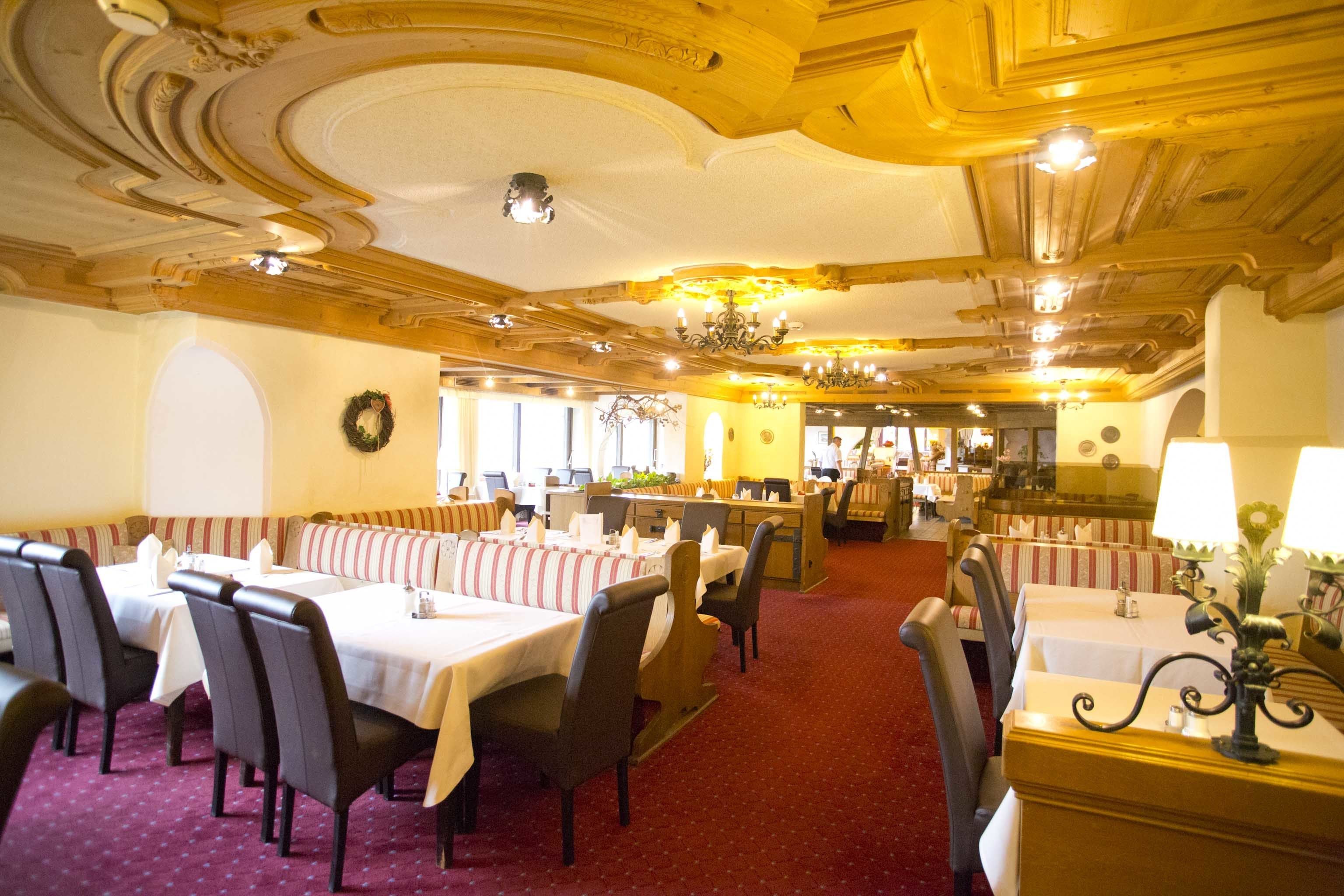 Un ristorante con una moquette rossa, tavoli bianchi e banconi a righe.