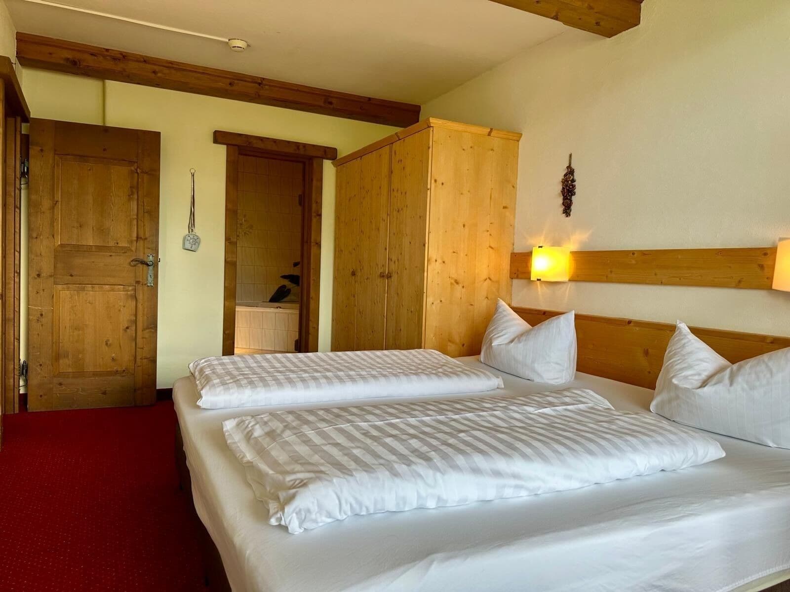 Ein Zimmer mit zwei Betten, Holzwänden, einem roten Teppich und einer Holzbodenverkleidung.