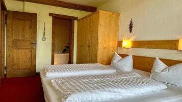 Ein Zimmer mit zwei Betten, Holzwänden, einem roten Teppich und einer Holzbodenverkleidung.