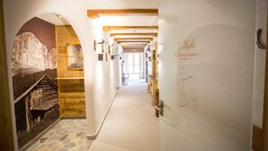 A corridor with wooden beams, stone flooring, and a mural of a mountain. - Berghotel Tirol (Jungholz)
