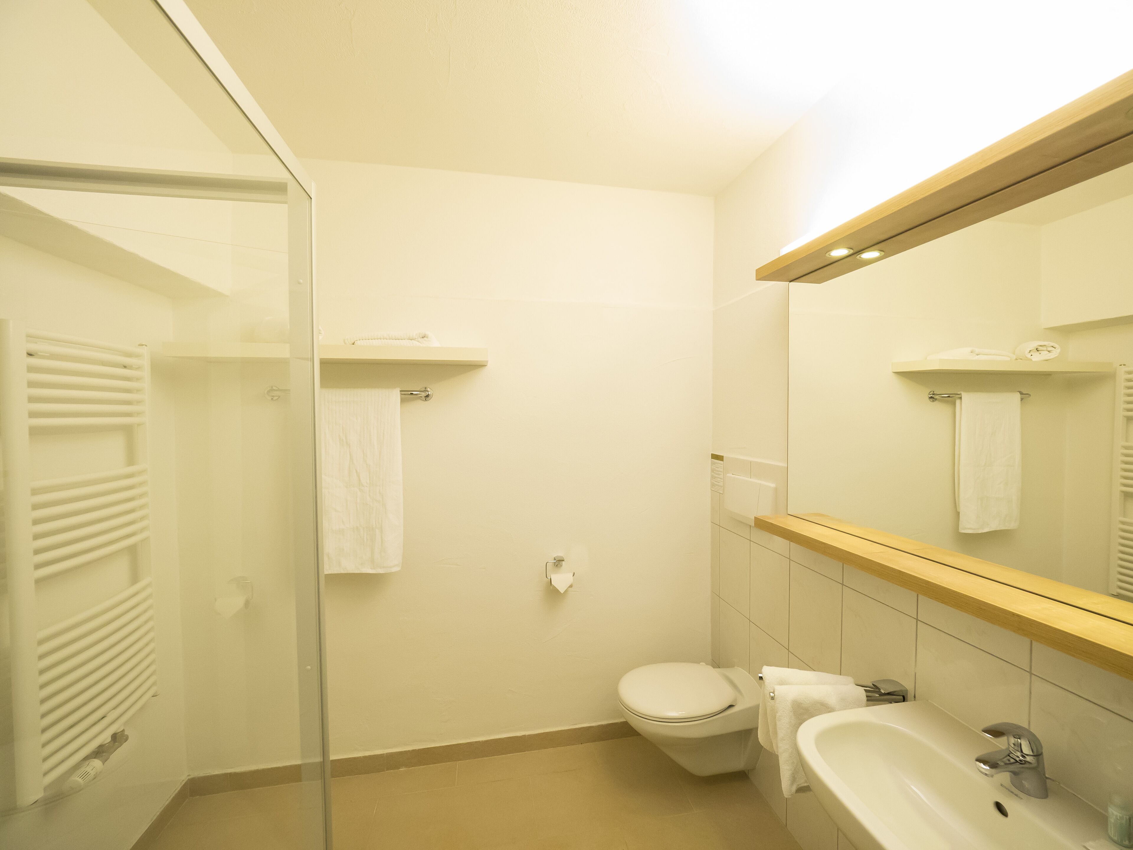A bathroom with a toilet, sink, and glass shower enclosure.