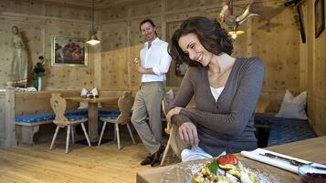 A wooden interior with a dining table, chairs, and a bench.