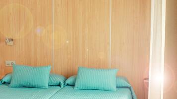 Una habitación con pared de paneles de madera, cama con ropa de cama color turquesa y una lámpara colgante.