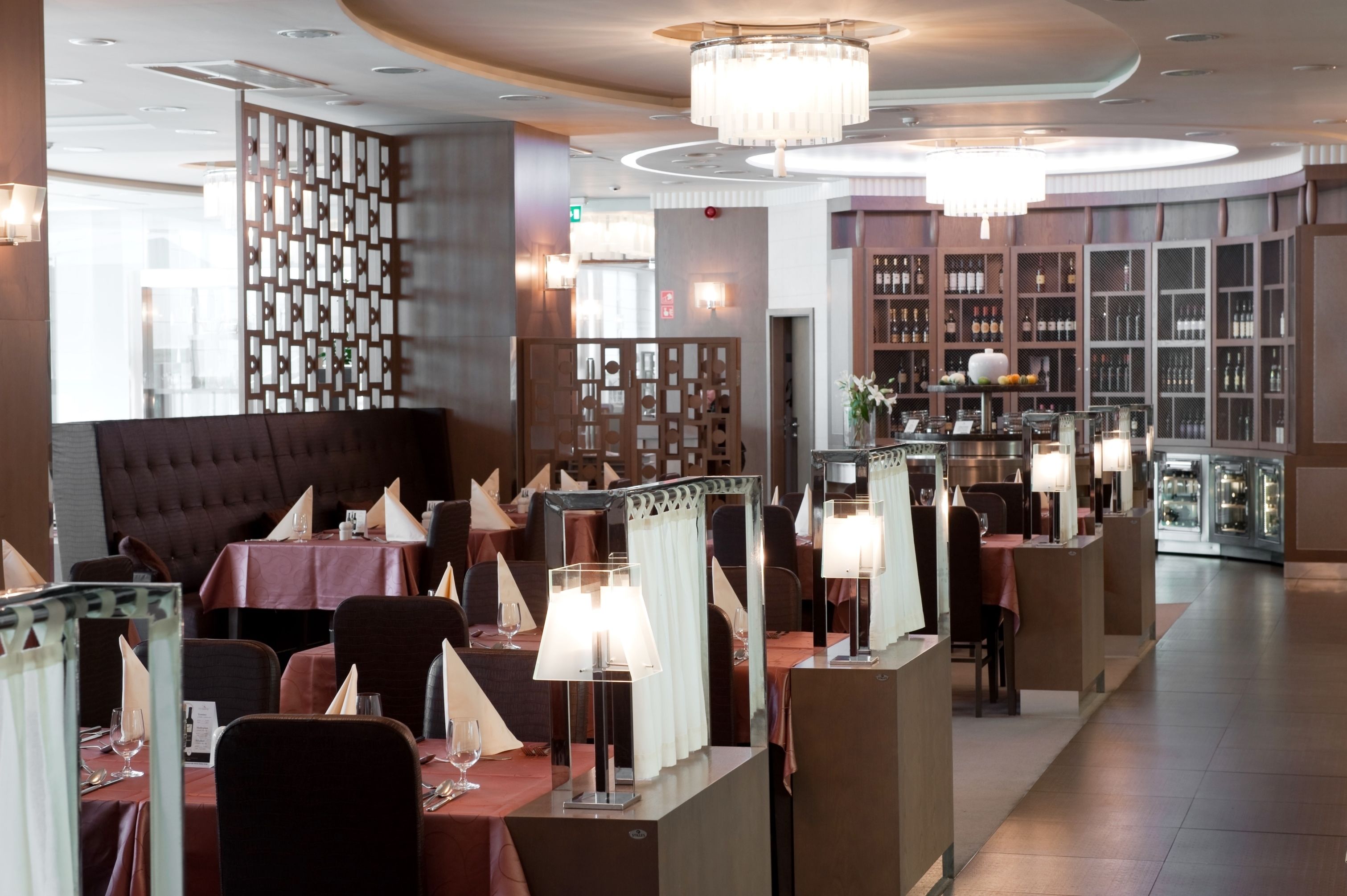 Un restaurant avec des tables dressées pour le service, un coin bar et un présentoir à vin.