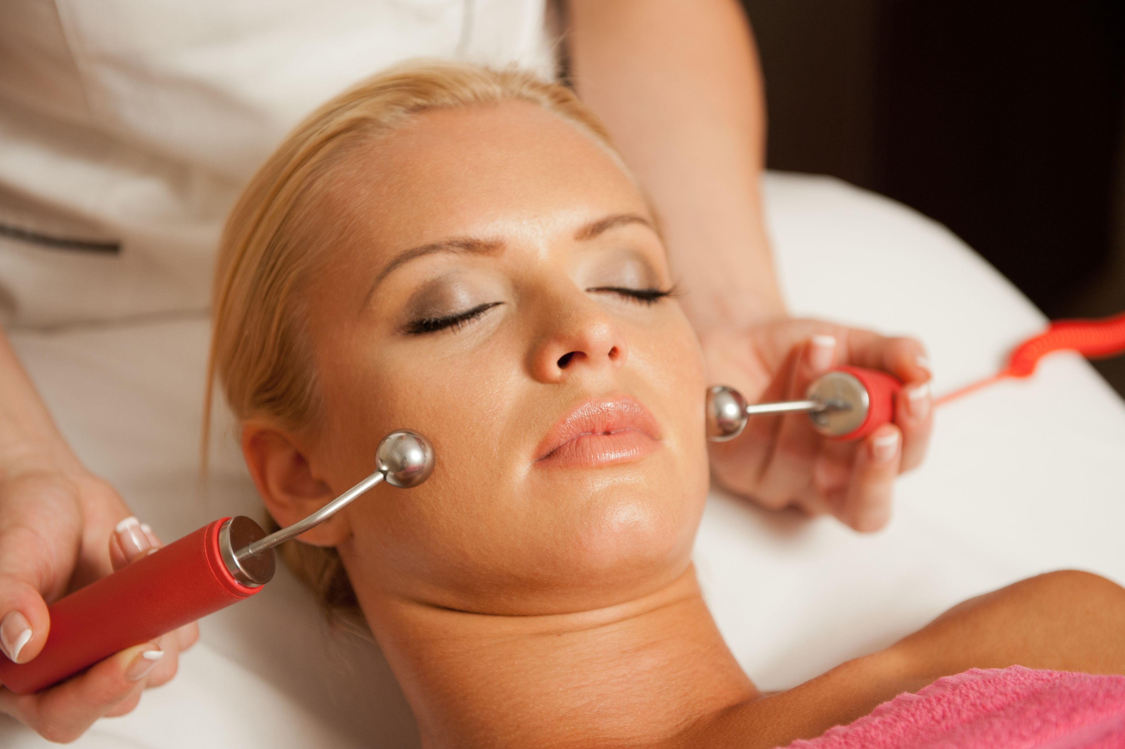 A person lying down with a medical device being used on their neck.