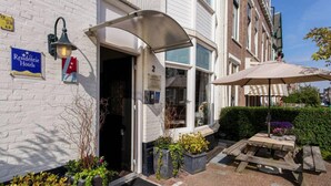 A hotel entrance with a covered patio, outdoor seating, and a sign for "Residentie Hotels". - Hotel 't Witte Huys (The Hague)