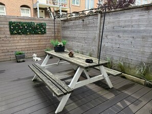 A wooden picnic table with benches, surrounded by a wooden fence and potted plants. - Hotel 't Witte Huys (The Hague)