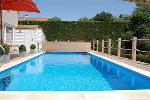 A rectangular swimming pool with a wooden deck and a rope barrier. - Hotel Rubens (De Haan)