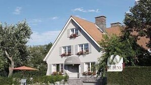 A two-story building with a pitched roof, a stone foundation, and a signboard. - Hotel Rubens (De Haan)