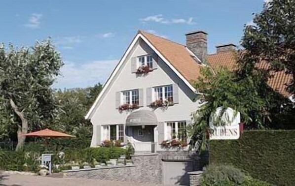 A two-story building with a pitched roof, a stone foundation, and a signboard. - Hotel Rubens (De Haan)