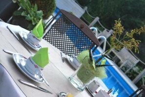 A dining table set with plates, cutlery, and a drink with a green garnish. - Hotel Rubens (De Haan)