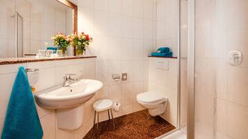 Une salle de bain comprenant un lavabo, des toilettes et un espace douche.