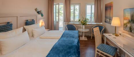 A hotel room with two beds, a desk, a chair, and a view of the outdoors.