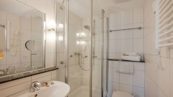 A modern bathroom with a glass-enclosed shower, a white sink, and a towel rack.