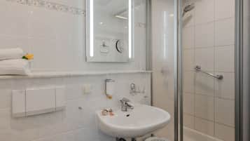 Un bagno moderno con lavandino bianco, specchio e cabina doccia in vetro.