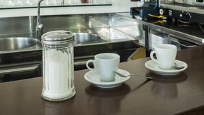 A bar area with shelves of liquor bottles, a coffee machine, and a sink. - Hotel Houston (Rimini)
