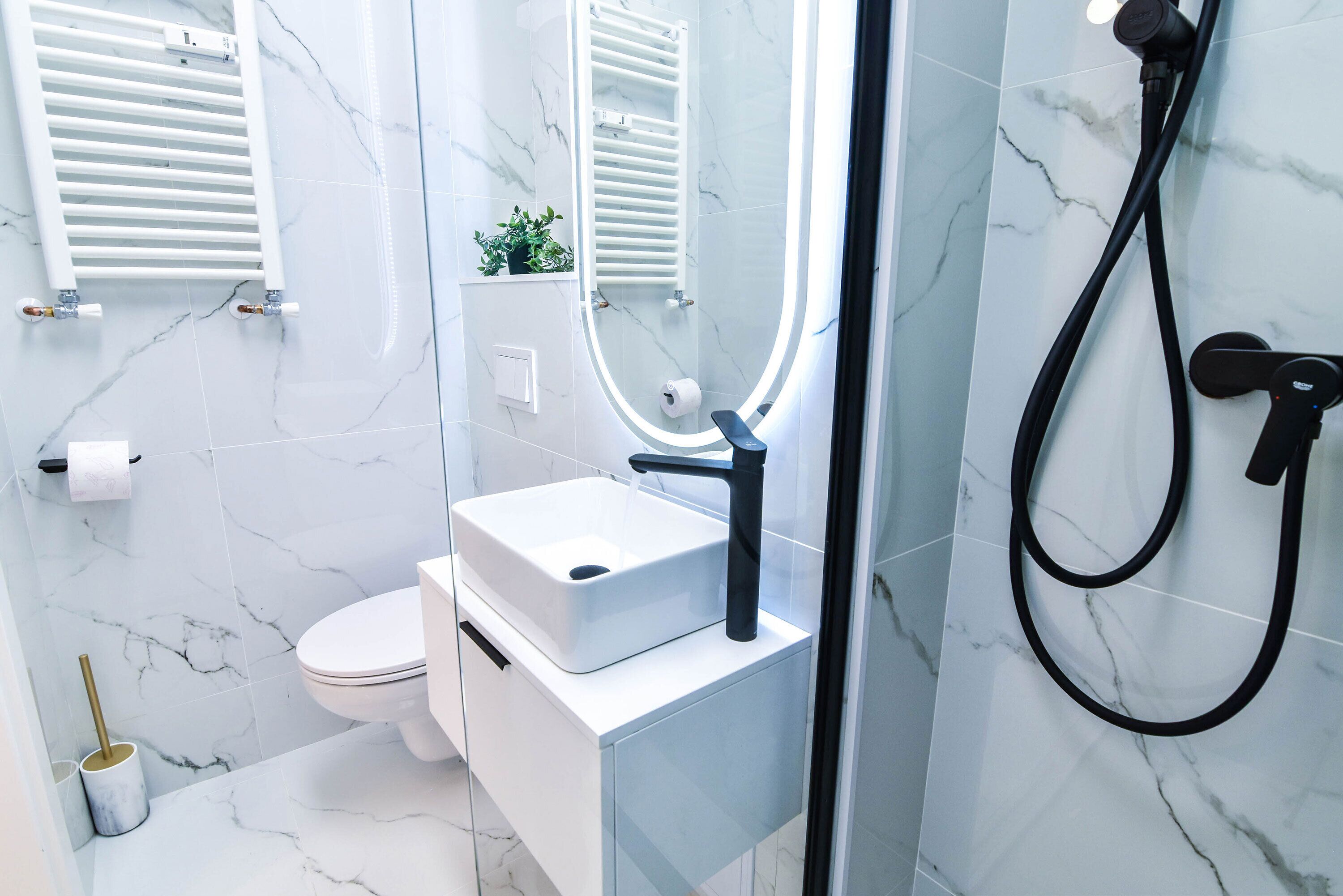 A modern bathroom with a white sink, toilet, and shower.