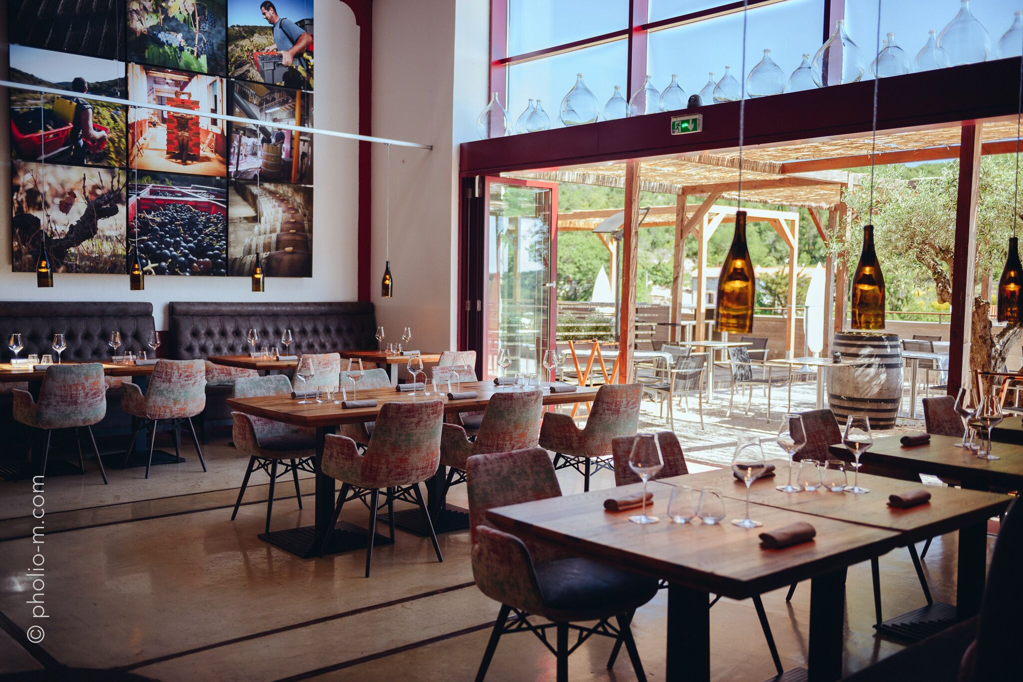 Un restaurante con un amplio salón comedor, varias mesas y sillas. Hay copas y botellas de vino sobre las mesas.