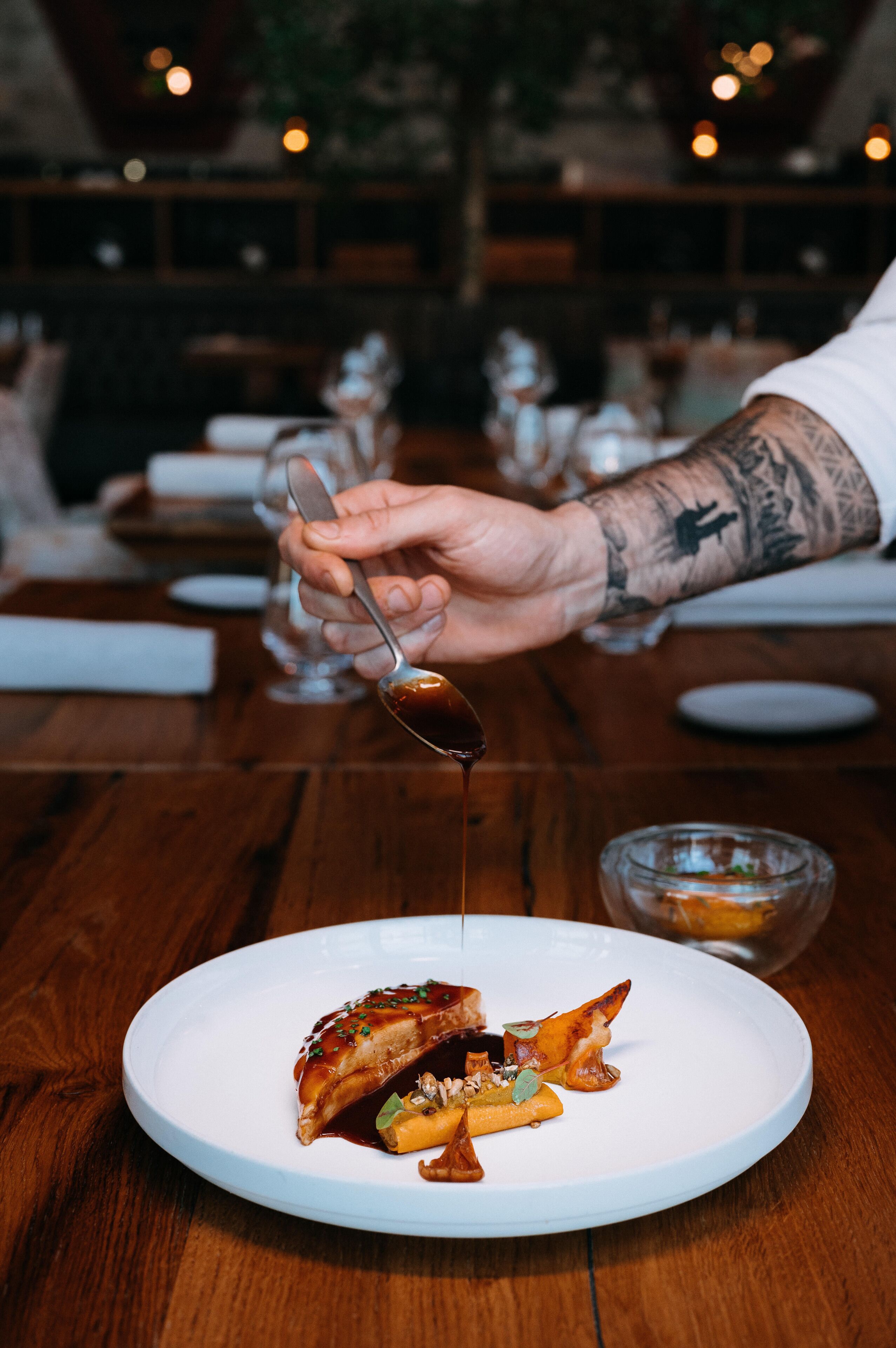 A person serving a dish on a white plate with a spoon.