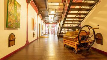 A corridor with wooden flooring, a vintage cart, and a staircase with metal railings.