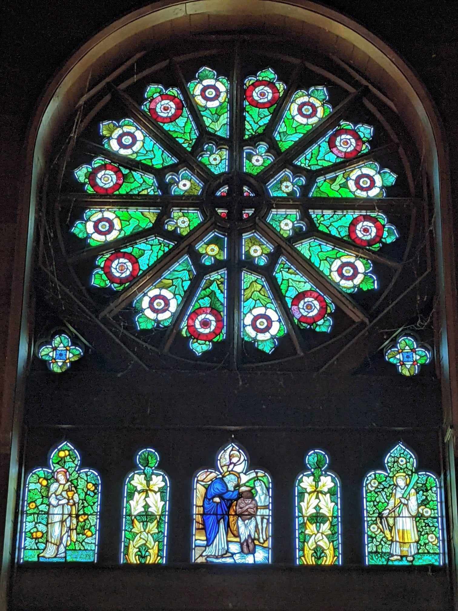 A stained glass window with a central circular design and four smaller panels below.