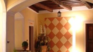 An indoor corridor with a tiled wall, wooden beams, and potted plants. - Hotel Casa Arizzoli (Cannobio)