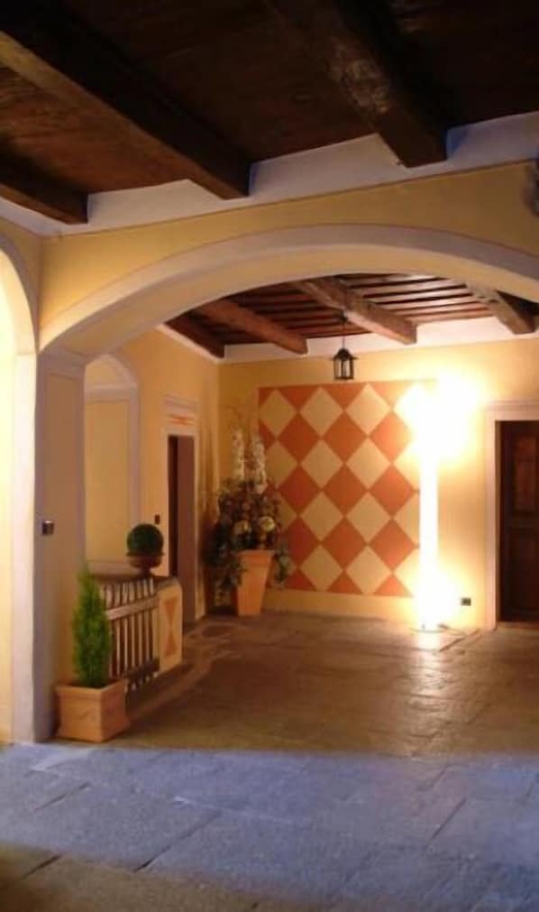 An indoor corridor with a tiled wall, wooden beams, and potted plants. - Hotel Casa Arizzoli (Cannobio)