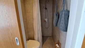 A small bathroom with a toilet, shower, and towel rack.