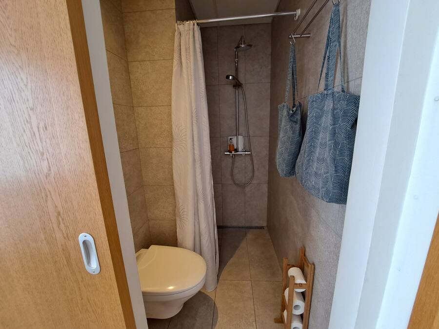 A small bathroom with a toilet, shower, and towel rack.