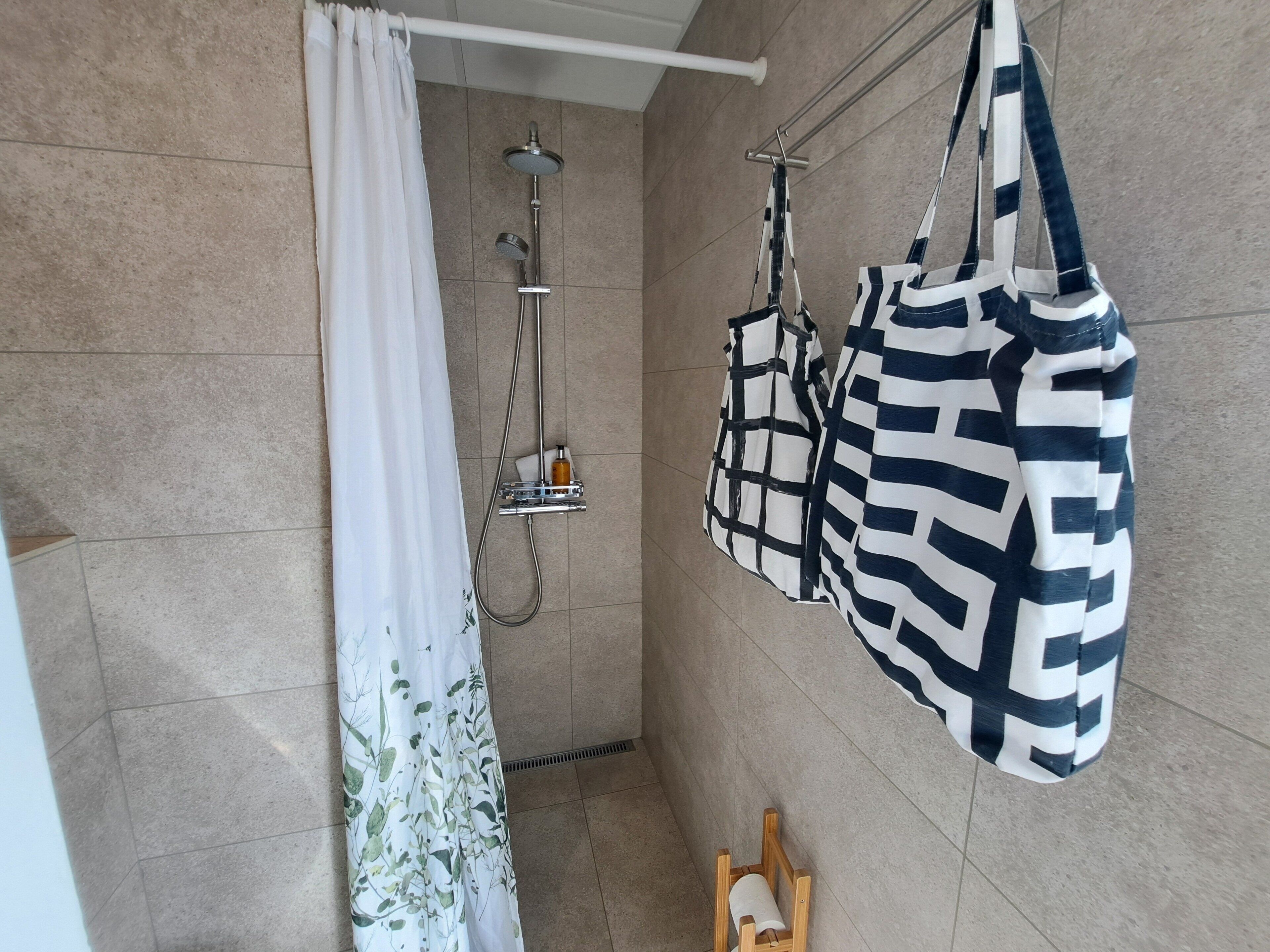 Un bagno con doccia, portasci e una sedia di legno.