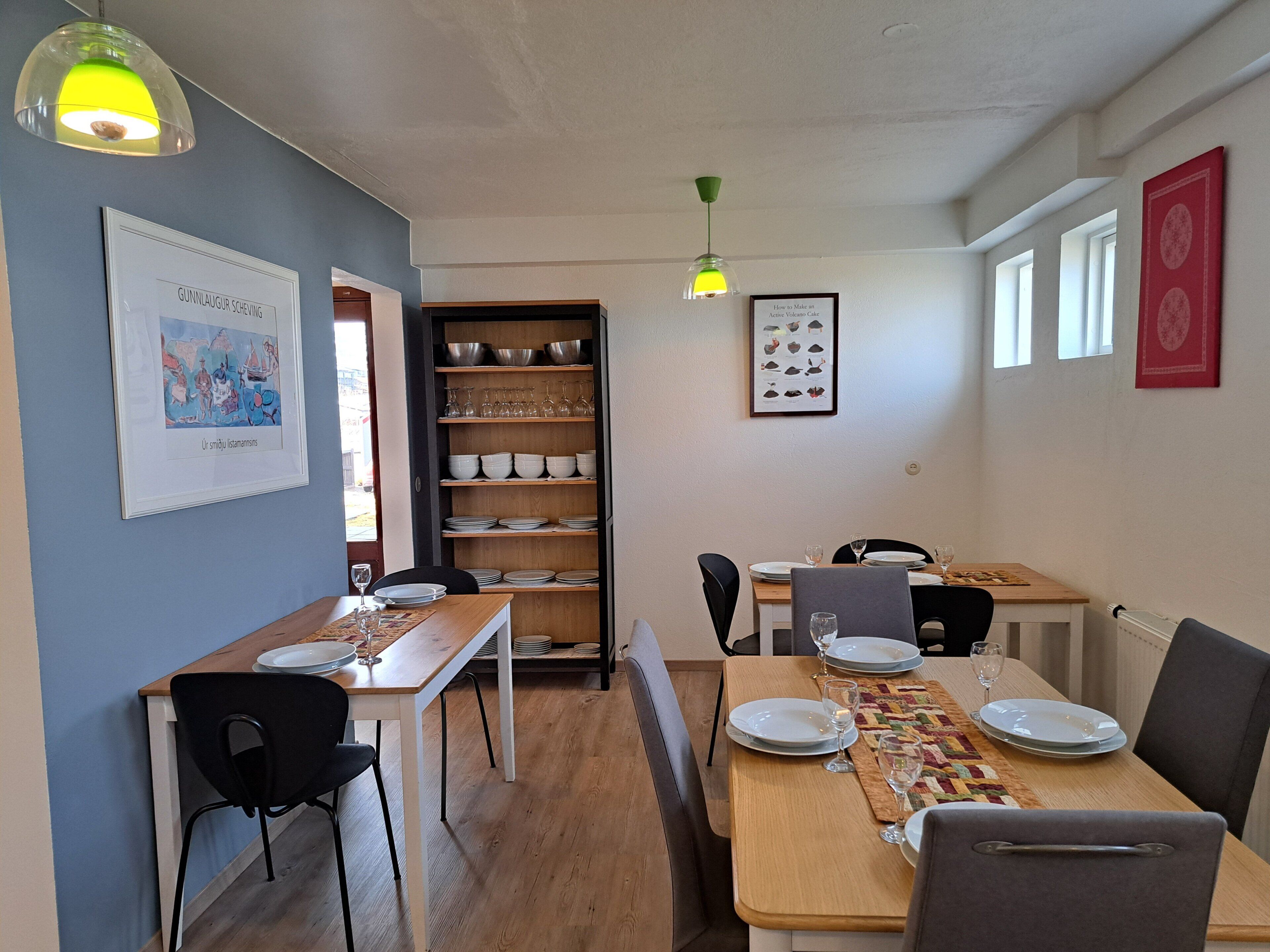 Un coin repas avec une table en bois, des chaises et une étagère où sont rangés la vaisselle et les verres.