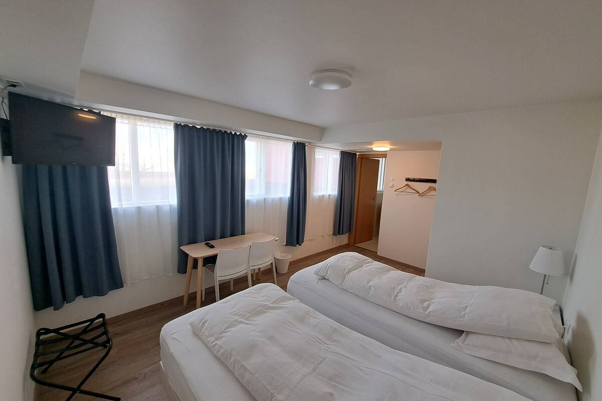 Una habitación de hotel con dos camas, un escritorio, una silla, un televisor y una lámpara.