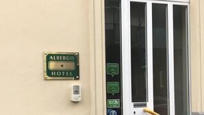 A hotel entrance with a door, a sign indicating it is Albergo Hotel, and a Wi-Fi symbol. - Hotel San Biagio (Milan)