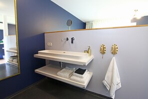 Ein Badezimmer mit einem weißen Waschbecken, einem Spiegel und zwei Handtüchern auf einem Regal.