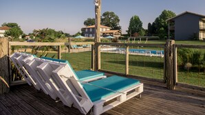 A wooden deck with lounge chairs and a pool. - La Petite Couronne, Ecolodge & Lofts (Saint-Cricq-Chalosse)