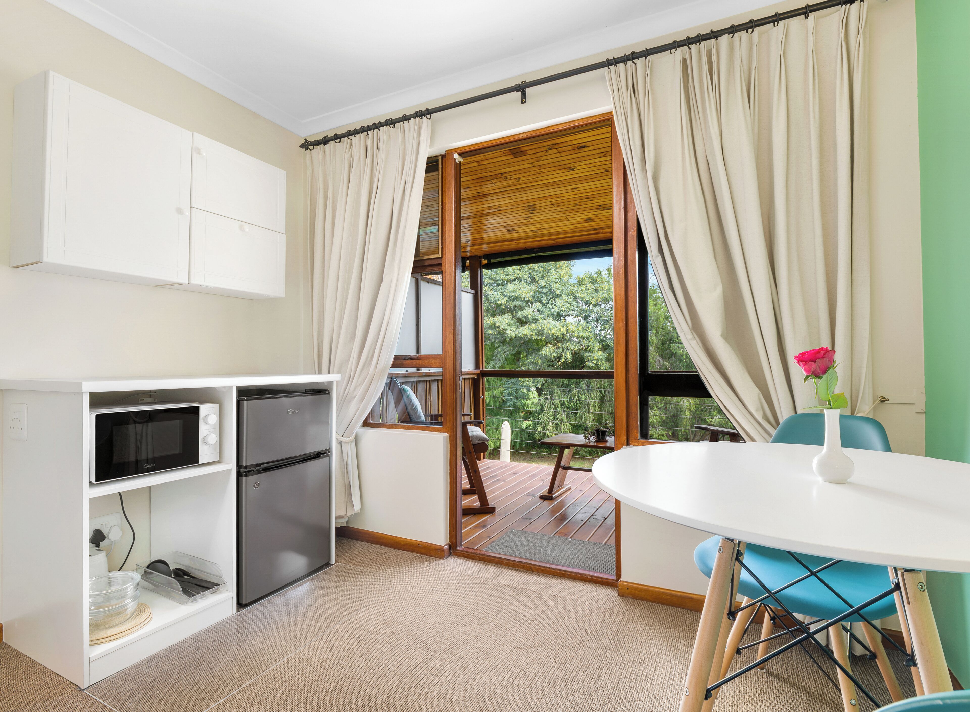 A compact kitchen with a microwave, refrigerator, and a dining area with a table and chairs.