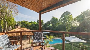 Une terrasse en bois avec des meubles d’extérieur, une piscine et une vue sur un jardin.
