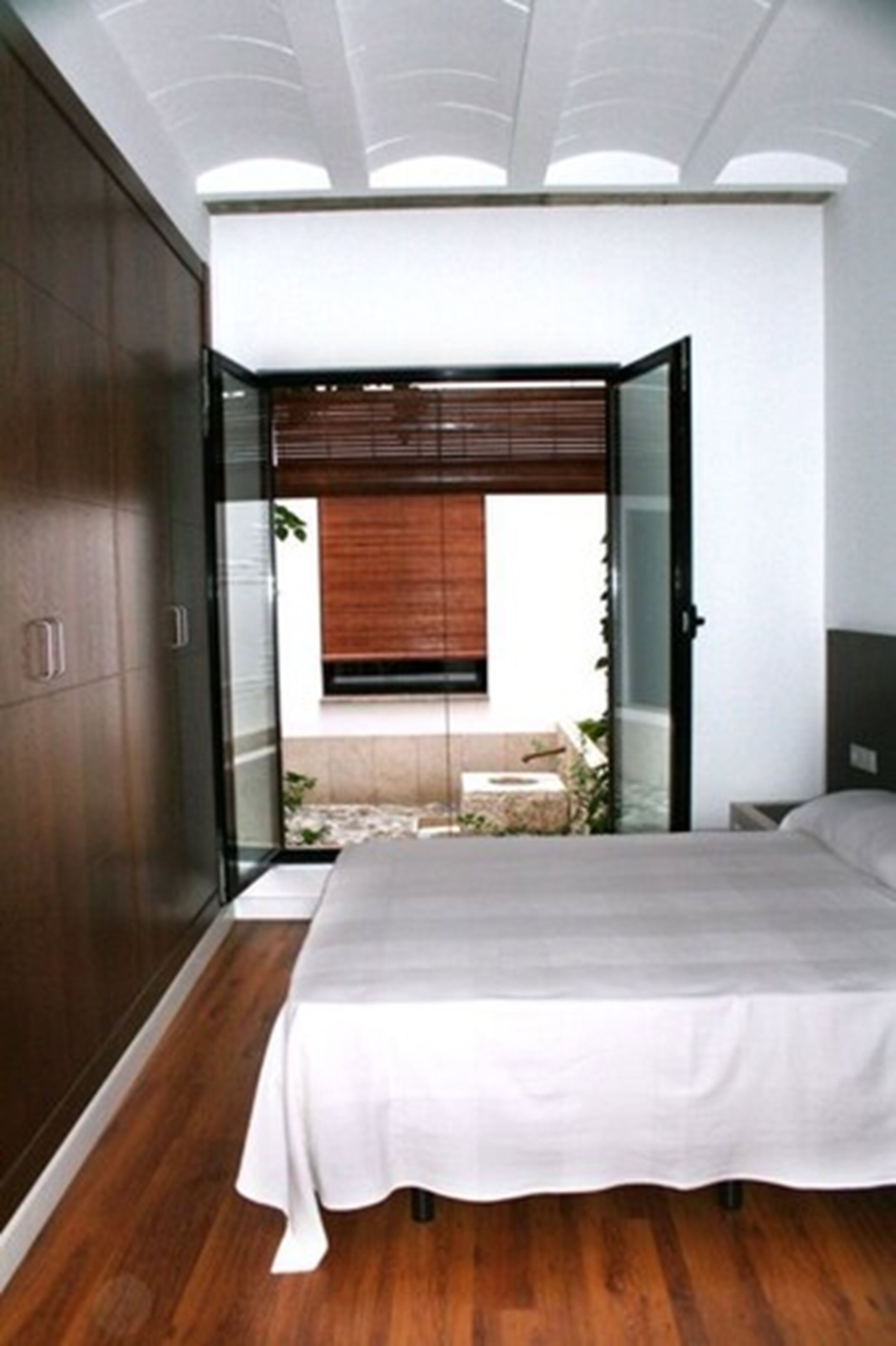 A bedroom with a bed, a wardrobe, and a sliding glass door leading to an outdoor area.
