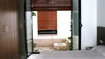 A bedroom with a bed, a wardrobe, and a sliding glass door leading to an outdoor area.