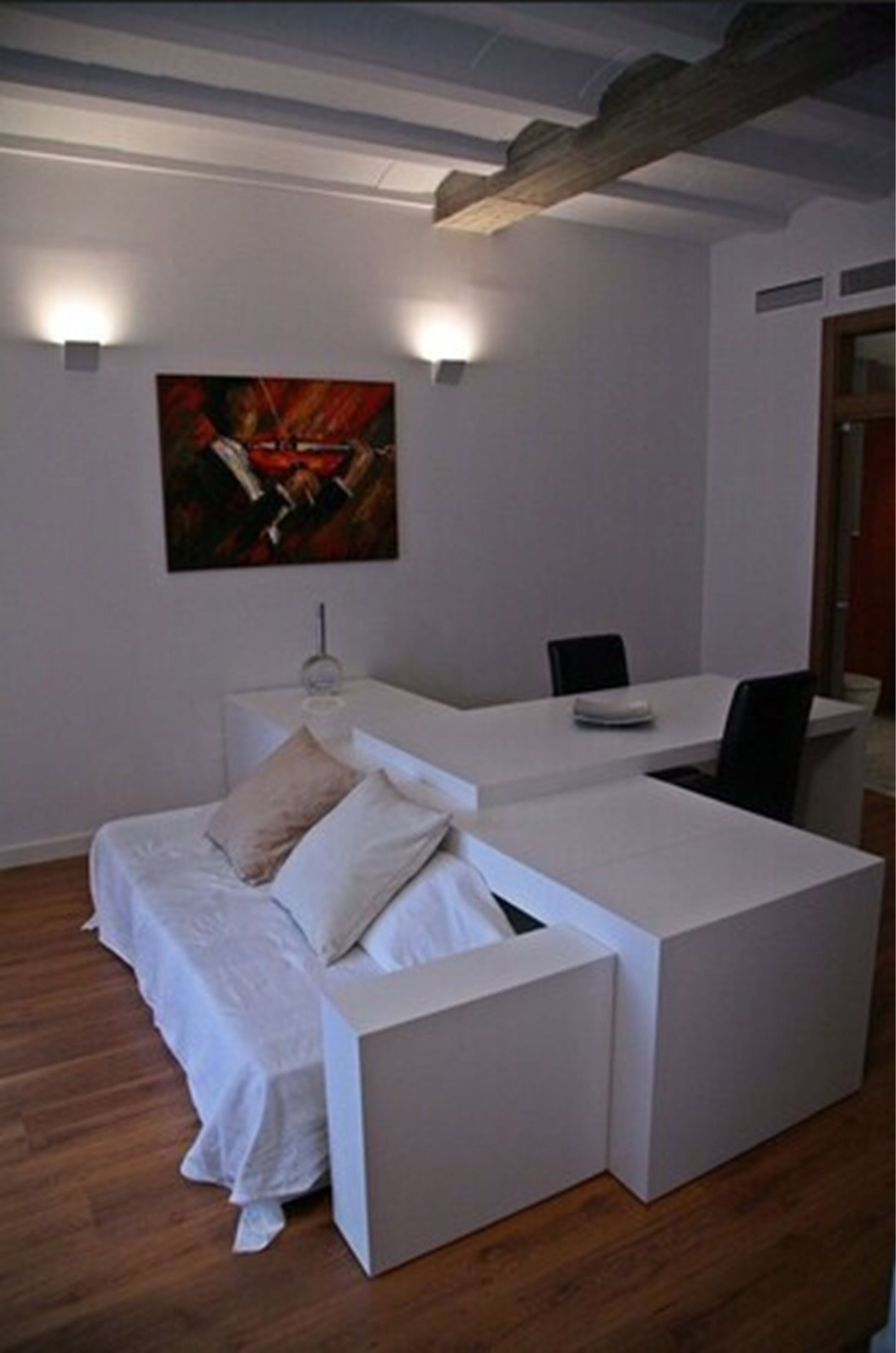 Ein modernes Zimmer mit einem weißen Sofa, einem kleinen Tisch und einem Bild an der Wand.