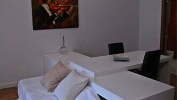 Ein modernes Zimmer mit einem weißen Sofa, einem kleinen Tisch und einem Bild an der Wand.