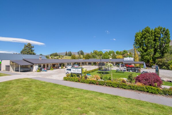 A motel with a parking lot, a covered outdoor seating area, and a sign indicating it is an Alpine Motel. - Alpine Motel (Wanaka)