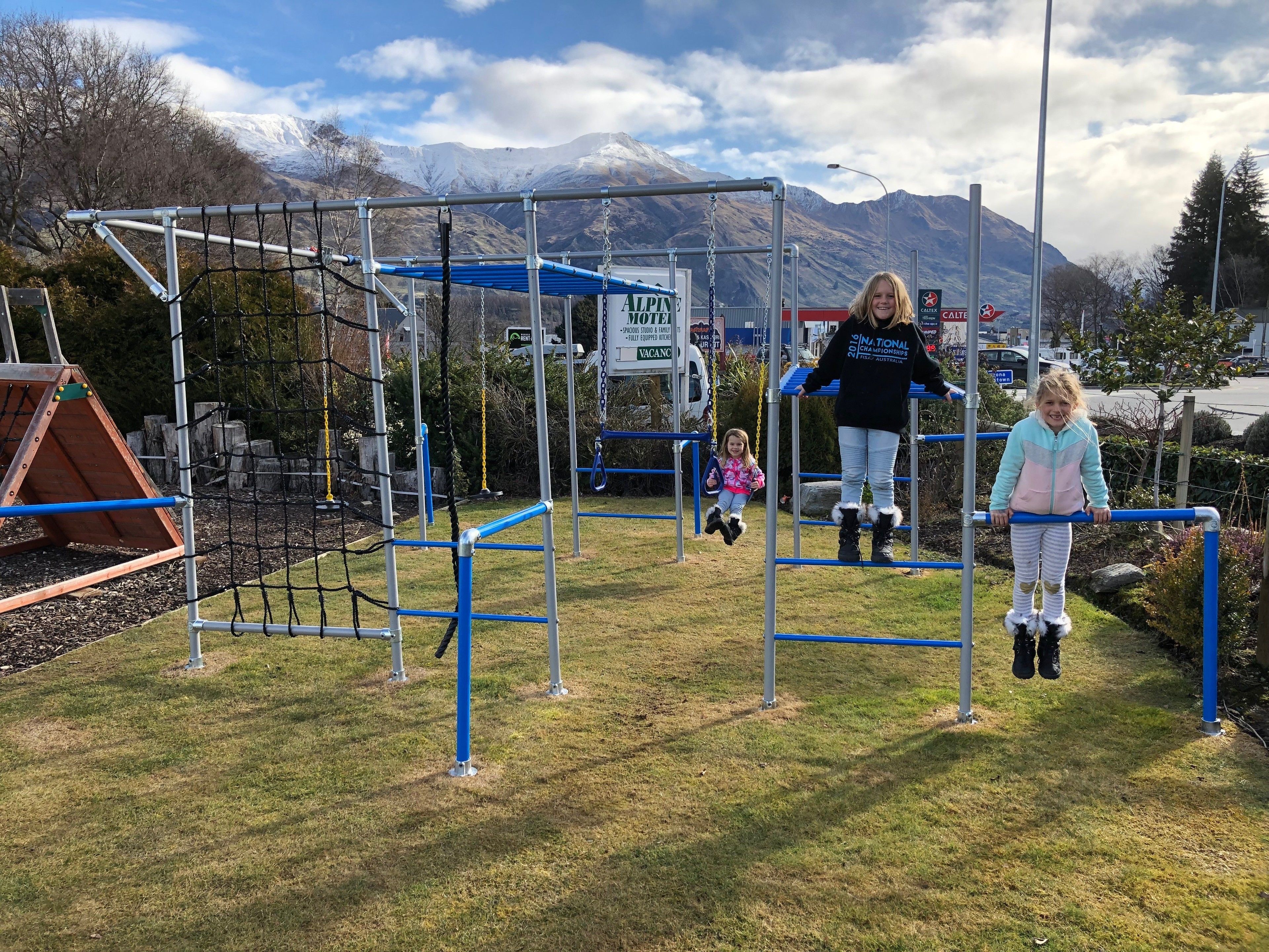 A playground with metal structures and a mountain backdrop.