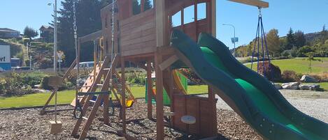 A wooden play structure with a slide and climbing elements.