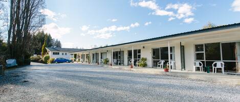 A building with a gravel driveway and a row of white chairs outside.