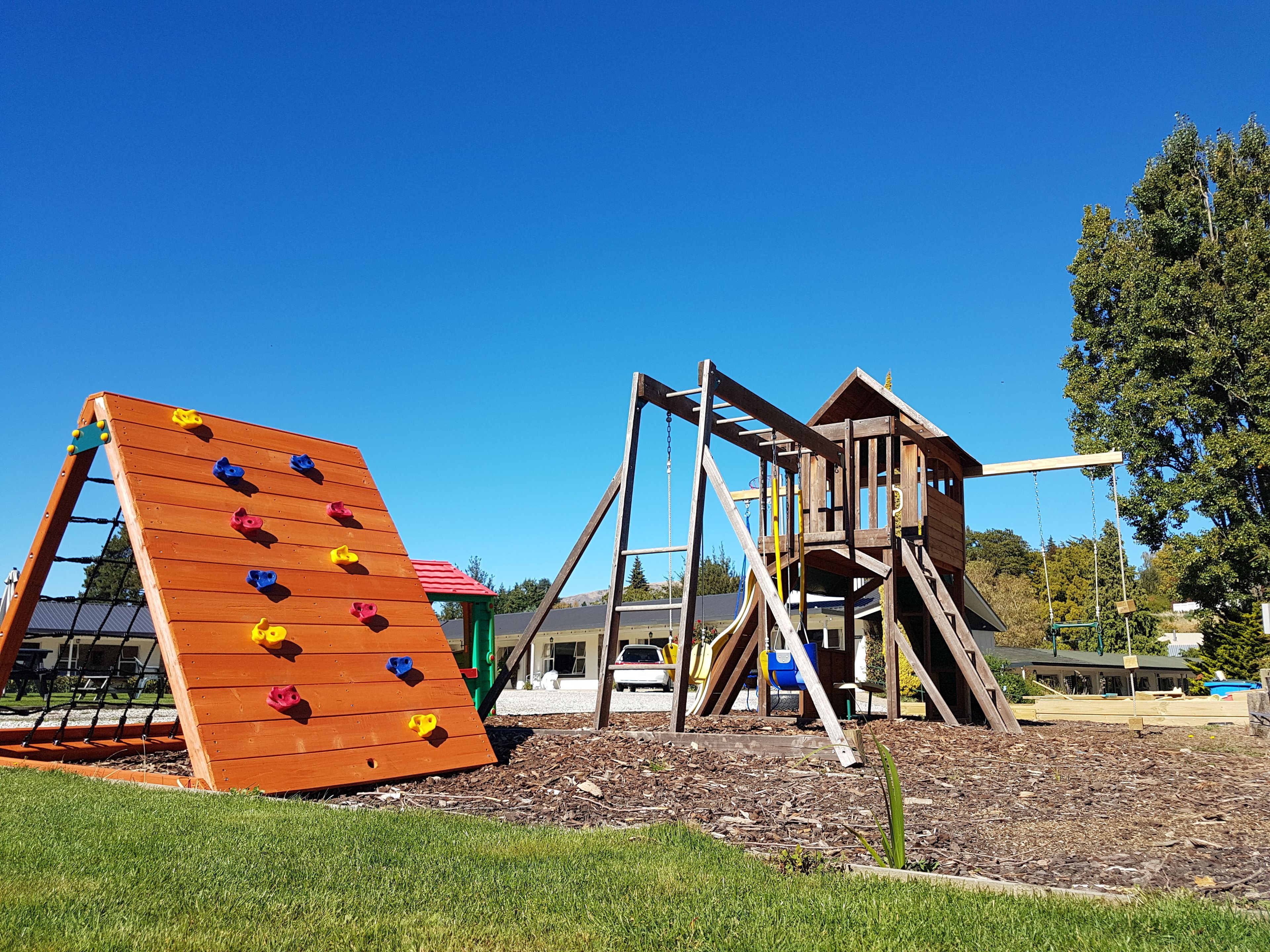 A playground with a climbing wall and a wooden play structure.