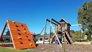 A playground with a climbing wall and a wooden play structure.