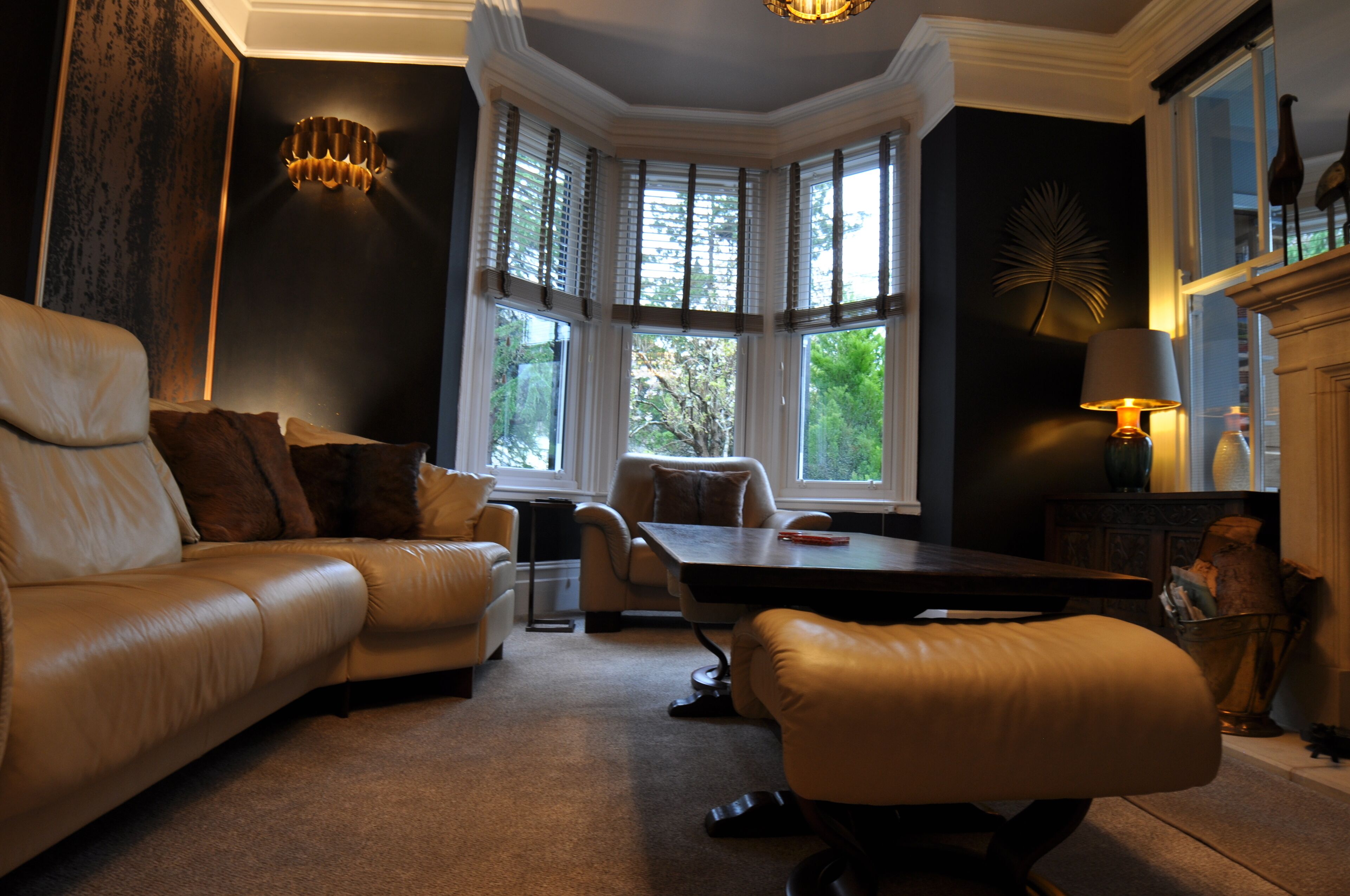 A room with a leather sofa, a dining table, and a fireplace.