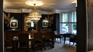 A formal dining room with a chandelier, wooden furniture, and a view of the outside. - Tir-y-Coed Country House (Conwy)